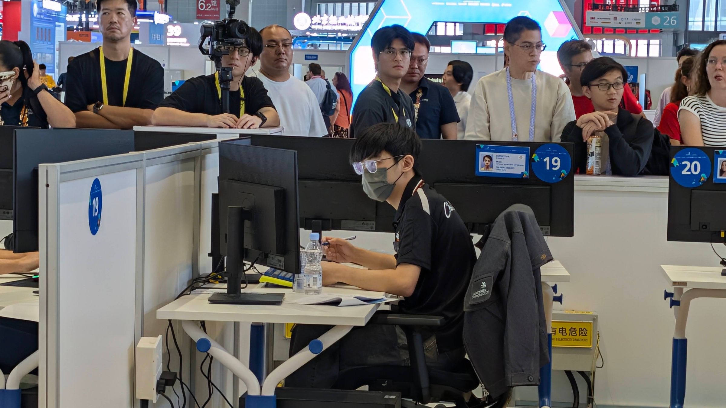 在上海的比賽工作站前作答,後方有觀眾觀看